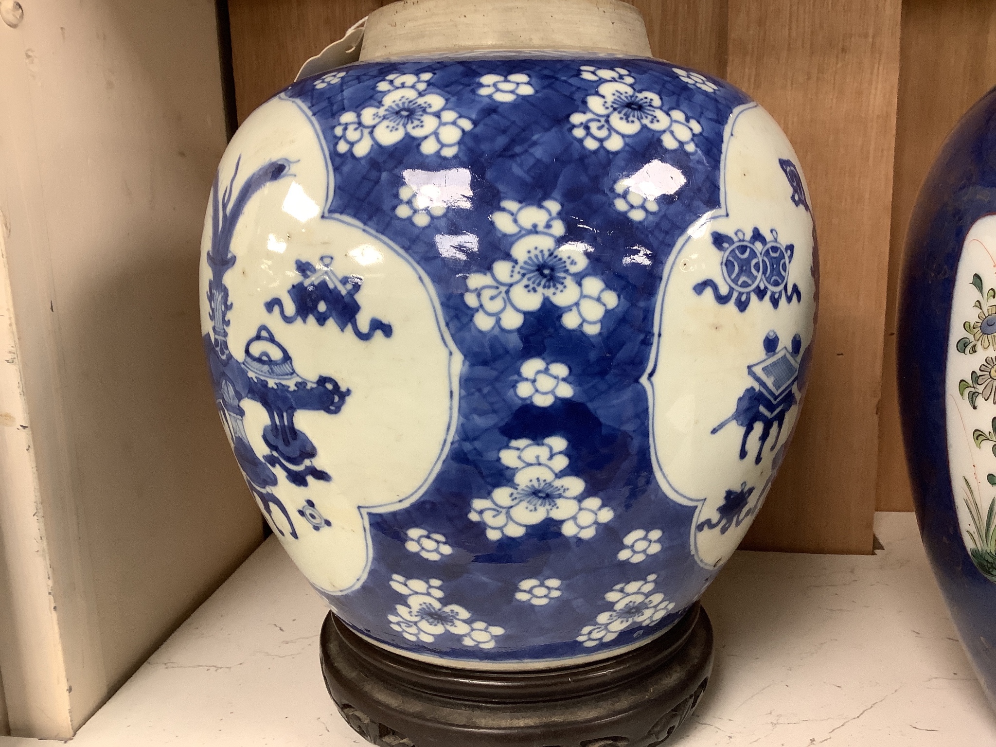 A Chinese Kangxi blue and white hundred antiques jar, 21cm, cracked, with hardwood stand and a Samson powder blue jar, 26cm, wear